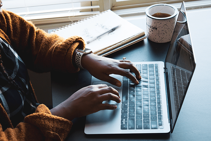 Image of someone's hands typing on the keyboard of their laptop